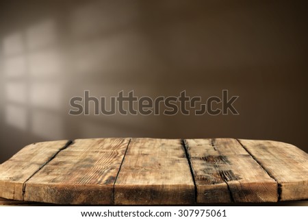 blurred brown wall with shadow space of window and shabby dirty wooden table 