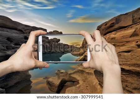 Girl taking pictures on mobile smart phone in Mountain stone cave 3000 boke in sunrise