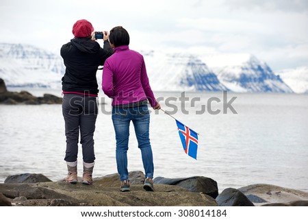 Girlfriends travelling together enjoying the scenery taking photos from the viewpoint in the westfjords, iceland. independent self drive holidays