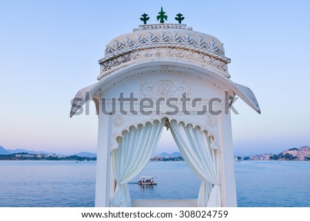 This is a horizontal, selective focus shot of a boat ride on Lake Pichola. This was shot at dusk from a viewpoint at the Island Palace in Udaipur, India. The lake shore is seen beyond.  Royalty-Free Stock Photo #308024759