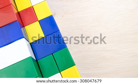 Bright colour building blocks on wooden surface. Concept of educational development tools. Slightly de-focused and close-up shot. Copy space.