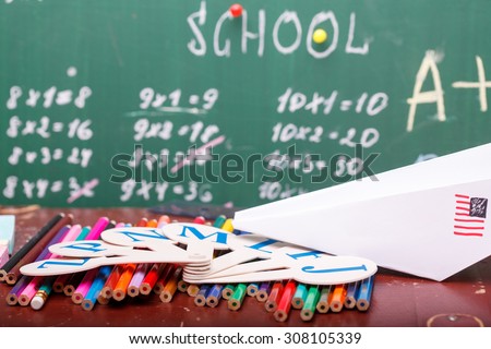 Blur texture background of school blackboard with written multiplication table and heap of colorful chalk blue pink violet, white yellow green colors lying on brown desk, horizontal picture