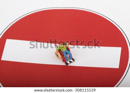 miniature of a disabled man on a wheelchair standing over a no entry sign