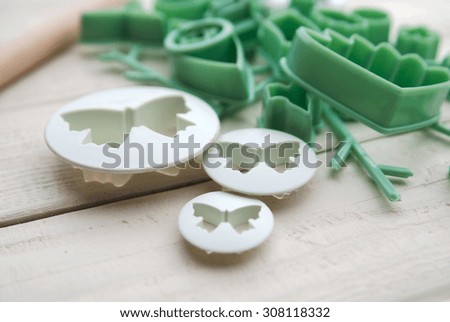 plungers in the form of butterflies and forms for mastic on a white wooden background