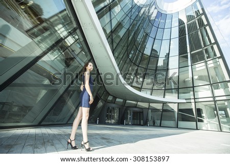 Beautiful young woman standing near the building of the business center.