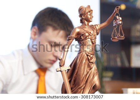 Justice statue and lawyer reading a book in the office