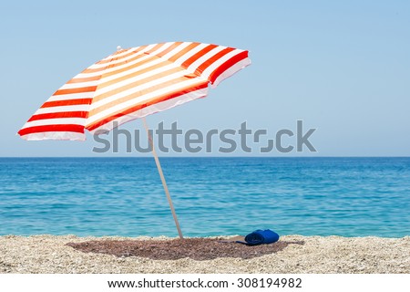 Striped beach umbrella on the beach. Royalty-Free Stock Photo #308194982