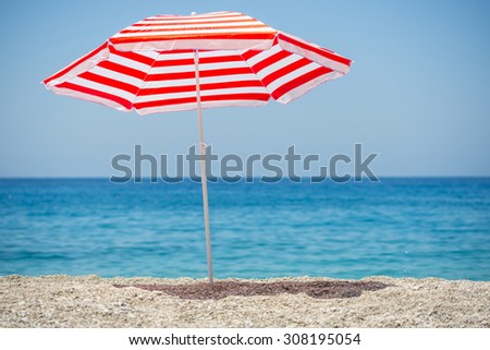 Striped beach umbrella on the beach. Royalty-Free Stock Photo #308195054