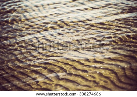 The bottom of the sea on the shore. Beautiful sandy waves created by the sea on the bottom sand. Image has a vintage effect applied.