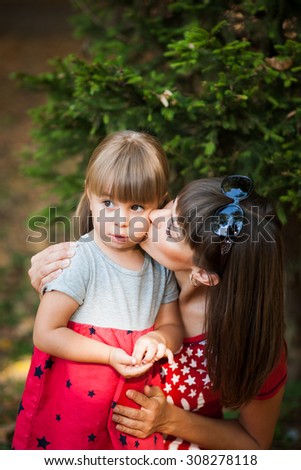 girl kissing her mother in a park in a clearing. Mothers Day
