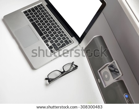 Business laptop and blank screen on wooden desk with glasses and stereo