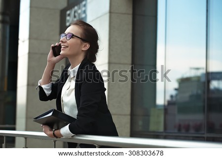 Business people - woman on smart phone, Young business woman office worker talking on smartphone smiling happy. Professional manager lady with phone and documents.