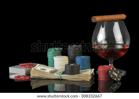 Poker chips and dollar bills with cognac glass on black background