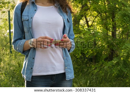 Young woman using a mobile phone during a hike with a backpack on nature. The use of satellite navigation.