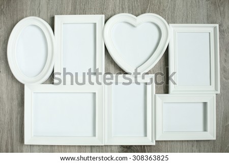 White photo frames of different shapes on the wooden background