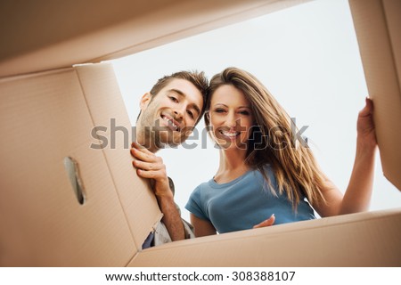 Smiling young couple opening a carton box and looking inside, relocation and unpacking concept Royalty-Free Stock Photo #308388107