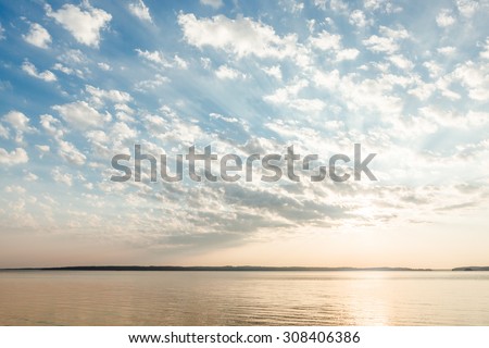 Clouds and sun rays over lake at sunrise Royalty-Free Stock Photo #308406386