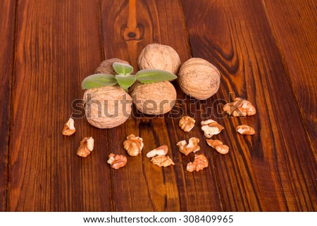 Walnuts with shell and green leaves on the wooden table