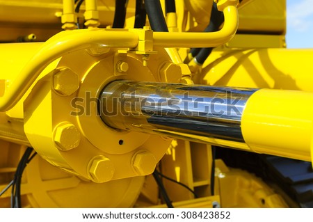 Hydraulic piston system for bulldozers, tractors, excavators, chrome plated cylinder shaft of yellow machine, construction heavy industry detail, selective focus Royalty-Free Stock Photo #308423852