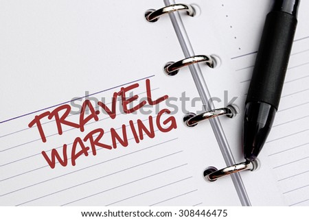 TRAVEL WARNING word written on notebook