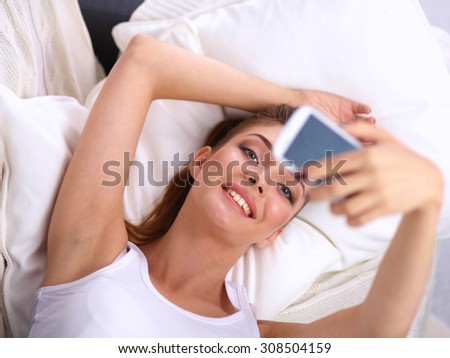Happy brunette taking a photo of herself with her mobile phone in  bedroom