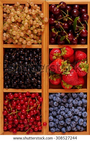 Bright picture in a wooden kitchen set laid out fresh berries strawberry, raspberry, red yellow and black currant, cherry