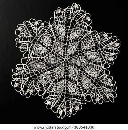 Crocheted white lace decorative napkin on black
