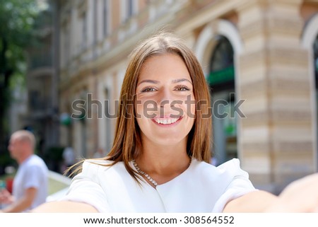 Smiling woman taking a selfie photo in an urban street 