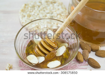 Nuts and honey in  a glass dish next to a glass with honey. Healthy dessert