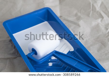 White paint in blue tray with paint roller, close up 