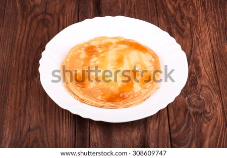 Pile of pancakes with apricot jam on a white plate on dark wooden background
