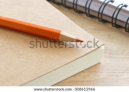 a note book and colored pencil on wood background
