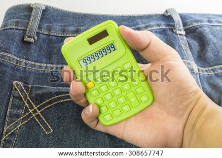 hand holding a calculator on jean texture background ,focus on calculator
