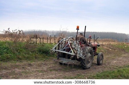 Farmer on old tractor cramps stubble on his field in Serbia. Preparing the country for the autumn plowing.