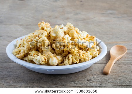 Popcorn in a white cup on a wooden background.