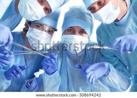 Below view of surgeons holding medical instruments in hands 