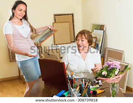 Excited buyer selecting the picture in the artist's studio. Selective focus
