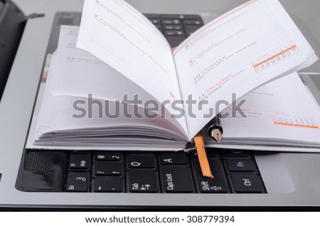 computer with notebook and a pen