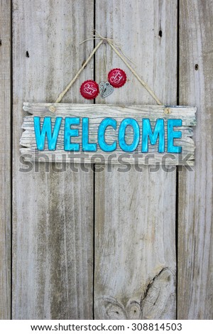 Rustic welcome sign with red soda bottle caps hanging on antique wooden background