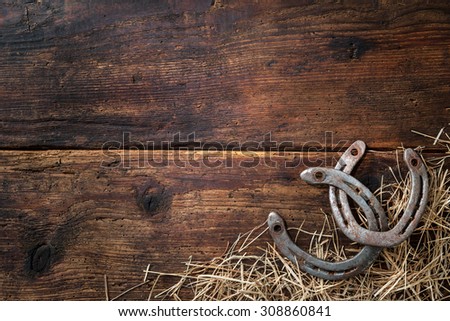 Two old rusty horseshoes with straw on vintage wooden board Royalty-Free Stock Photo #308860841