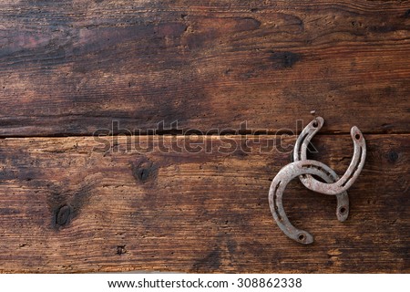 Two old rusty horseshoes on vintage wooden board