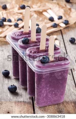 Homemade popsicles with blueberry and yogurt  on wooden rustic background