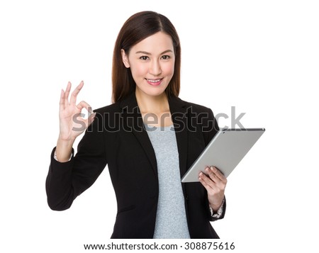 Asian young businesswoman use of the tablet pc with ok sign gesture