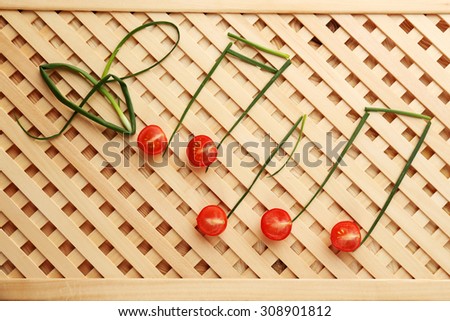 Treble clef and musical notes of green onion with tomato on striped background