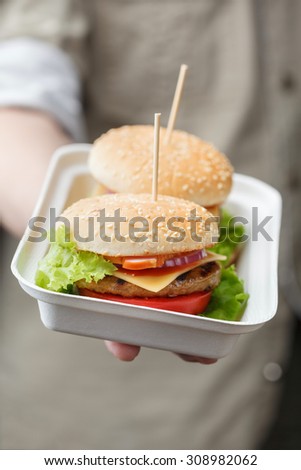 Container with two burgers in male hand