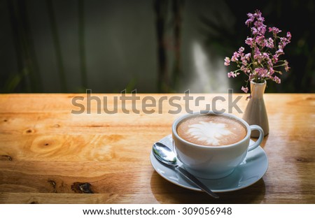 Hot latte art coffee cup with flowers on wooden table, vintage and retro effect.