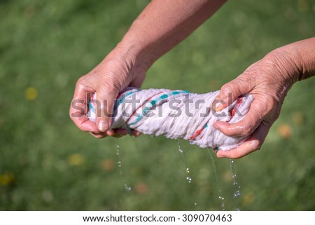 Hands squeeze wet fabric on a grass background