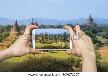 Girl taking pictures on mobile smart phone in sunrise on Pagoda in Bagan, Myanmar at day light