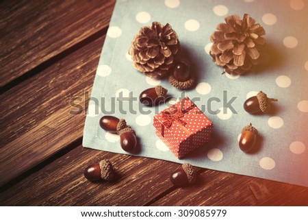Gift box and pine cones on wooden table.