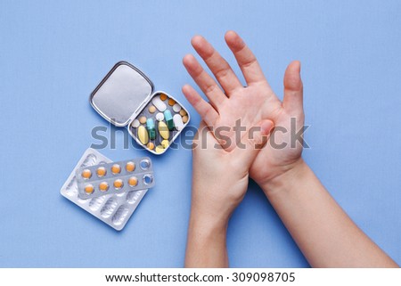 Woman hand with joint pain and pills on table